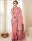 Woman wearing a pink saree with a decorative border in a well-lit room.