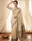 Woman wearing a beige saree with floral patterns in a room with white curtains.