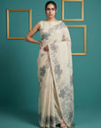 Woman wearing a floral saree against a teal background with gold frames.