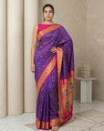 Woman wearing a purple saree with pink blouse in a neutral setting