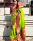 Woman wearing a bright green saree with a pink border on a rooftop.