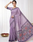 Woman wearing a purple saree with a floral border on a white background