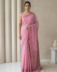 Woman wearing a pink saree with a neutral background