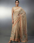 Woman wearing a beige saree with a subtle pattern on a gray background