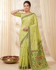 Woman wearing a light green saree with a floral border against a beige curtain background