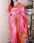 Woman wearing a pink and orange saree with a decorative border indoors.