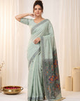 Woman wearing a light blue saree with a floral border against a white background