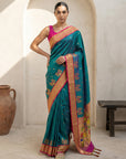 Woman wearing a teal saree with a pink blouse in a minimalistic setting.