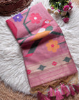 Pink scarf with floral and bird design on a white surface with flowers and a basket.