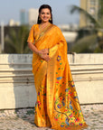Woman in a bright yellow saree with floral patterns standing outdoors.