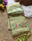 Light green scarf with floral patterns on a textured surface with flowers and a basket in the background.