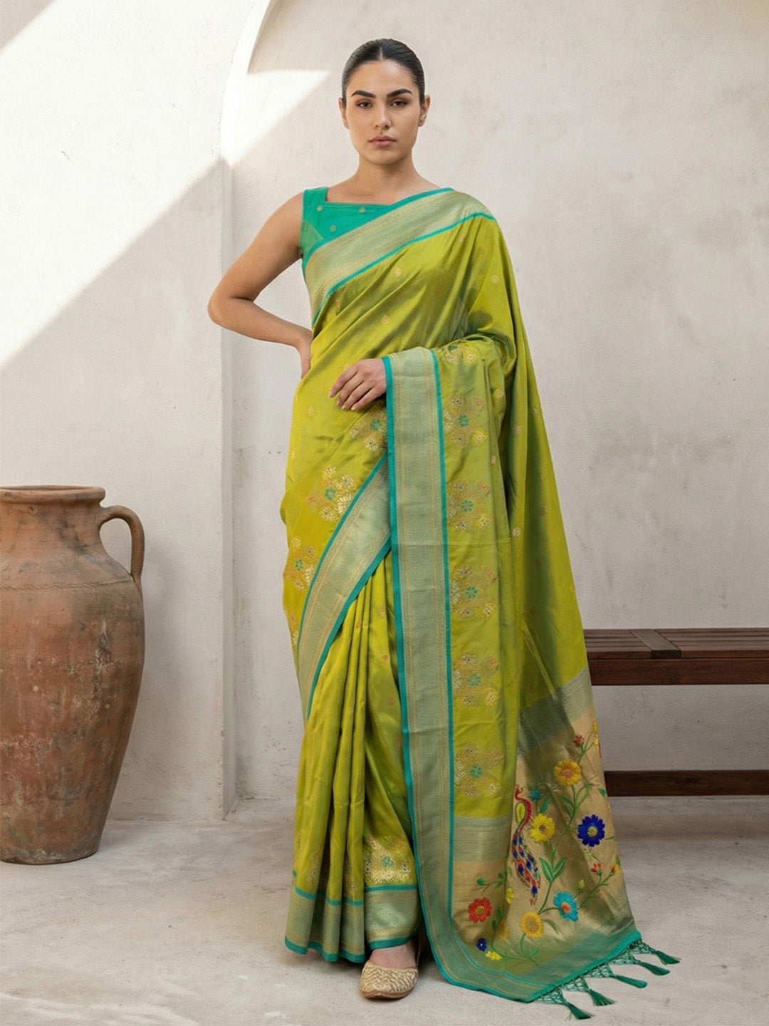 Woman wearing a green saree with floral patterns in a minimalistic setting.