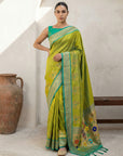 Woman wearing a green saree with floral patterns in a minimalistic setting.