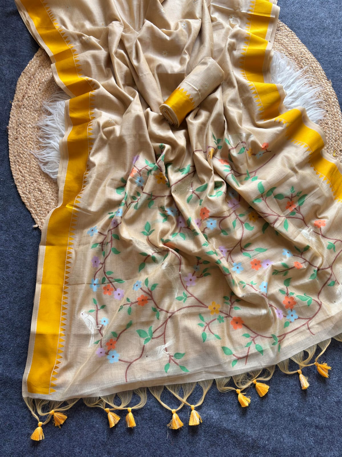 Beige fabric with floral patterns and yellow border on a blue background