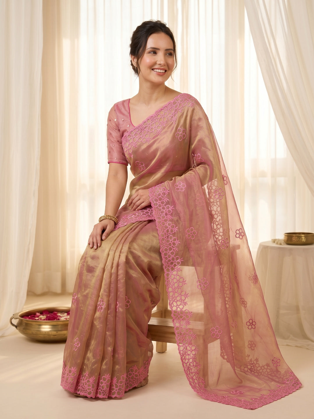 Woman wearing a pink saree with a matching blouse in a well-lit room.