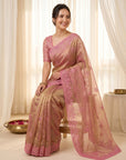 Woman wearing a pink saree with a matching blouse in a well-lit room.