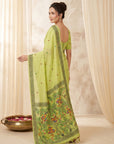 Woman wearing a green saree with intricate patterns in a neutral setting