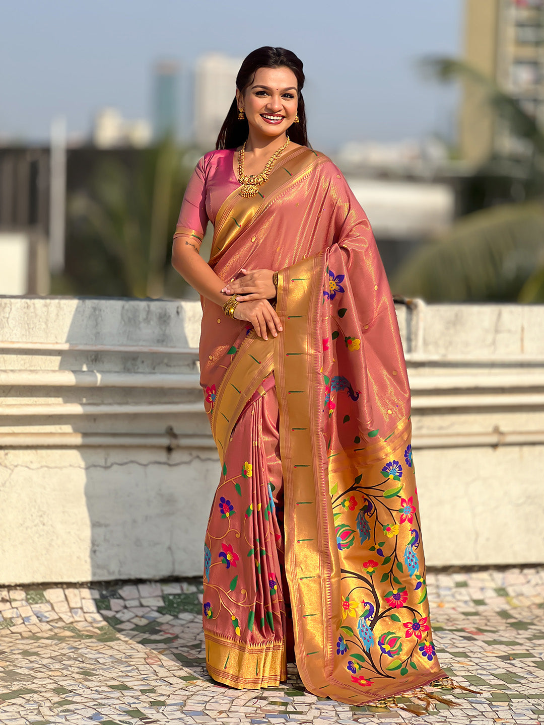 Woman wearing a traditional saree with a colorful design outdoors.