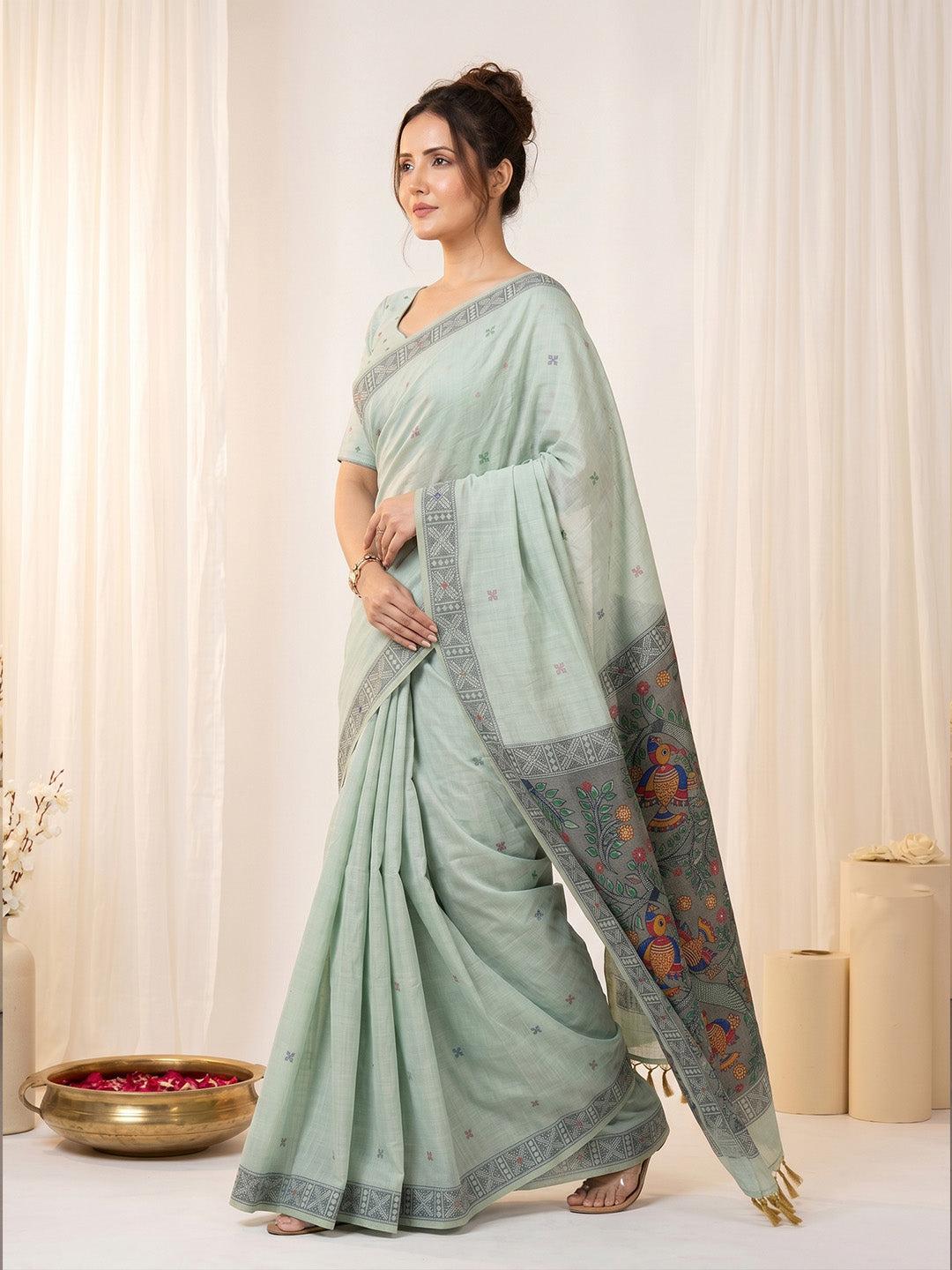 Woman wearing a light blue saree with a decorative border against a white background