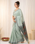 Woman wearing a light blue saree with a decorative border against a white background