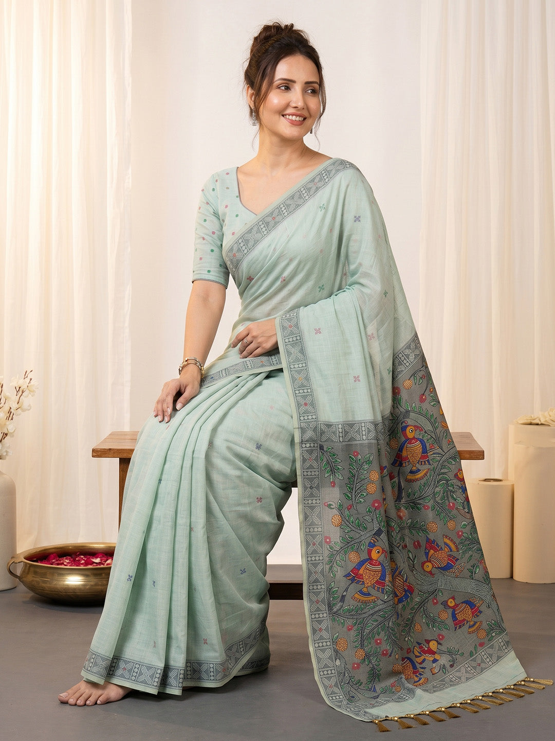 Woman wearing a light blue saree with a patterned border indoors.