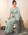 Woman wearing a light blue saree with a patterned border indoors.