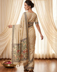 Woman wearing a traditional saree with a floral pattern in a room with white curtains.