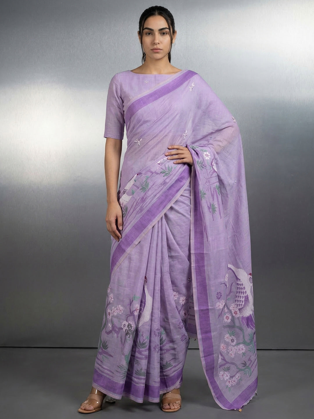 Woman wearing a lavender saree with a floral pattern on a gray background