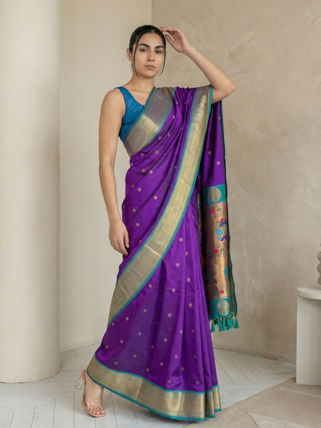 Woman wearing a purple saree with a blue blouse in a minimal indoor setting
