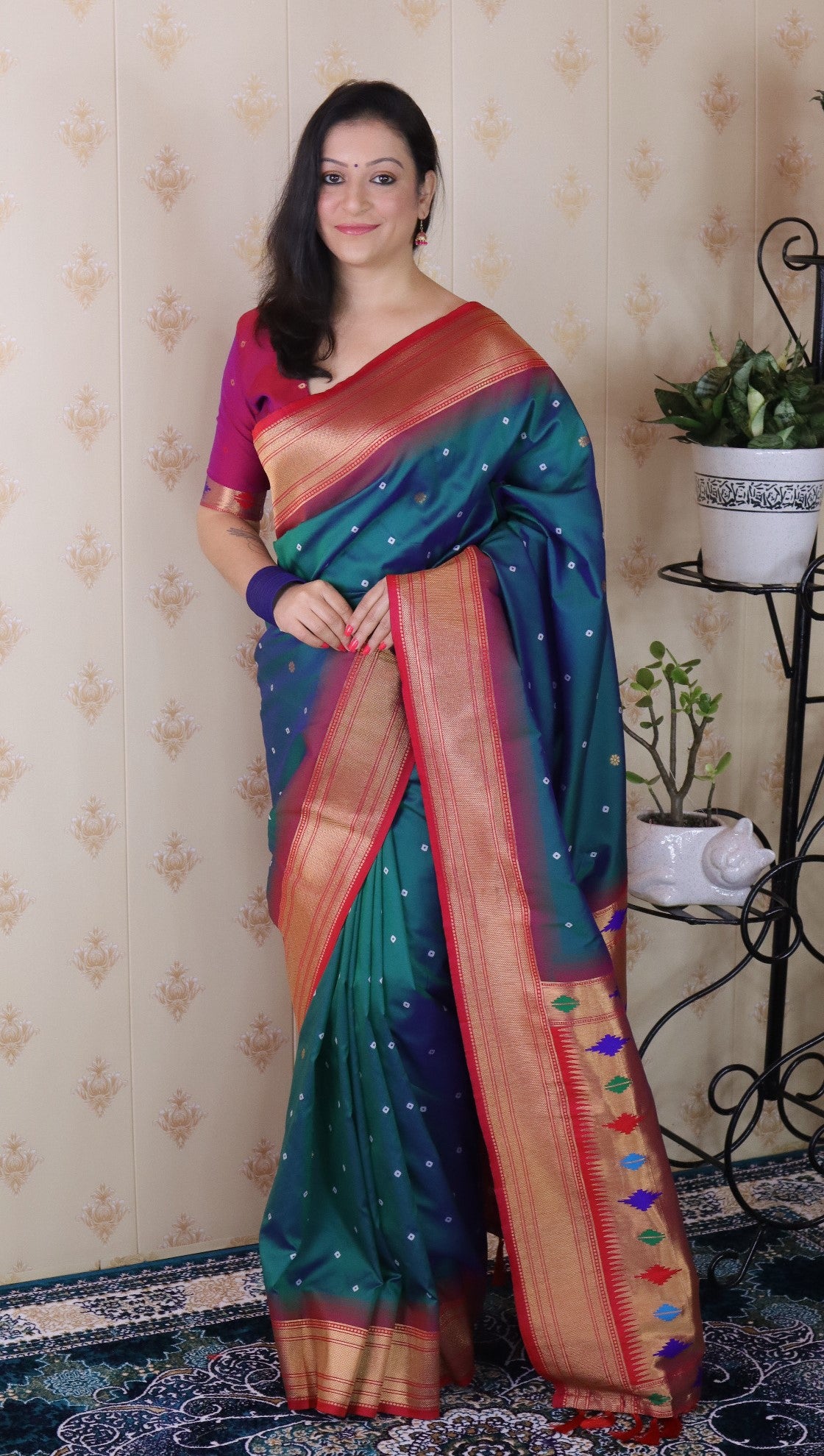 Woman wearing a colorful saree indoors with decorative elements.