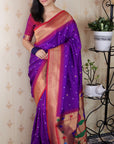 Woman wearing a purple saree with a patterned background