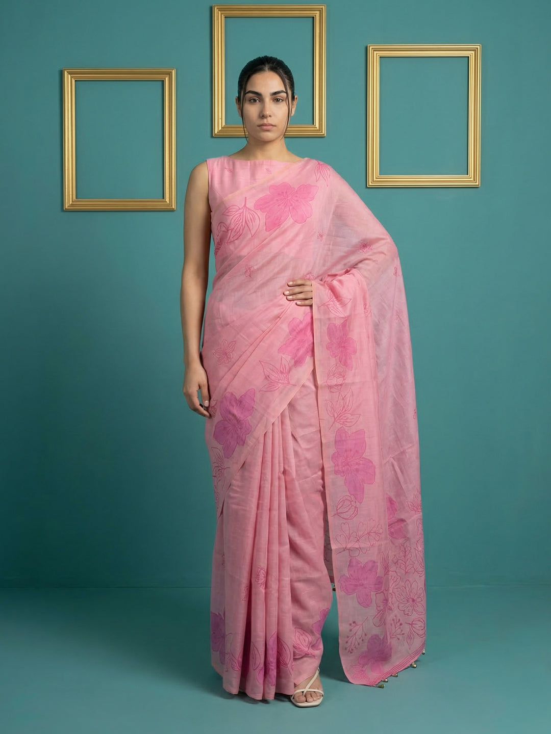 Woman wearing a pink saree with floral patterns against a teal background