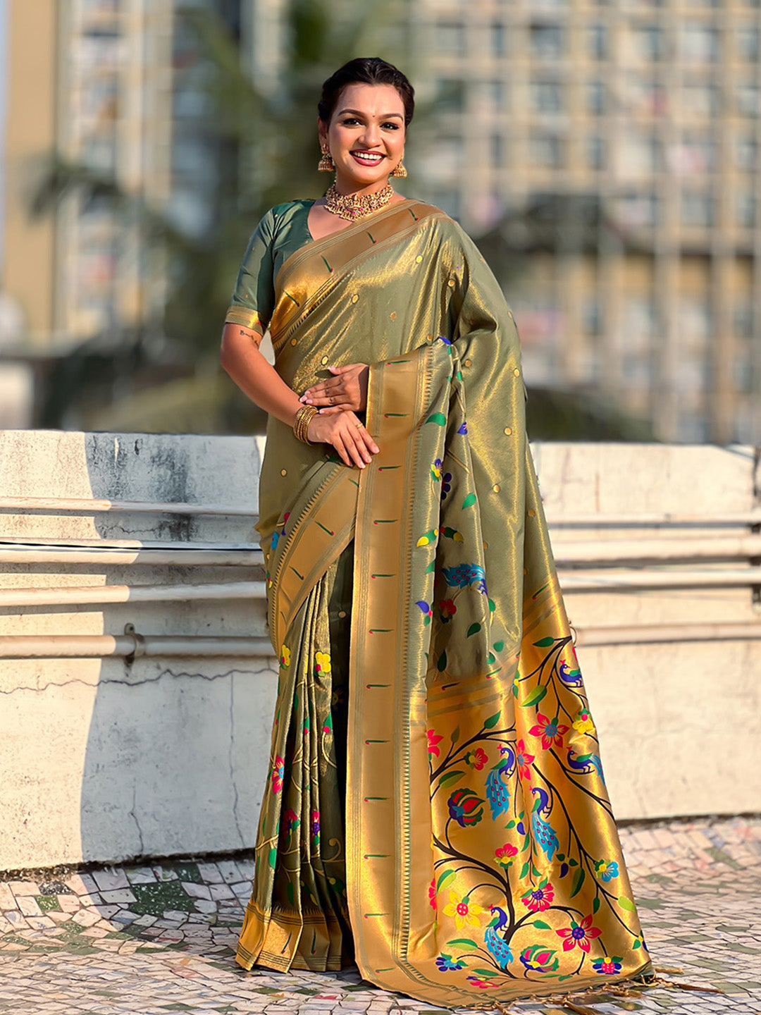 Woman in a traditional saree with floral patterns standing outdoors.