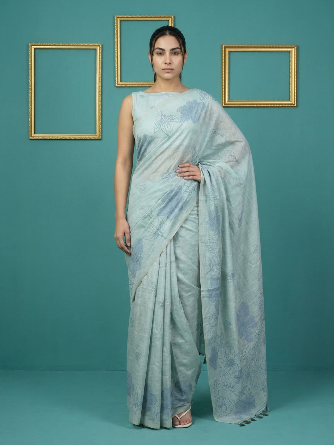 Woman wearing a light blue saree with a subtle pattern against a teal background