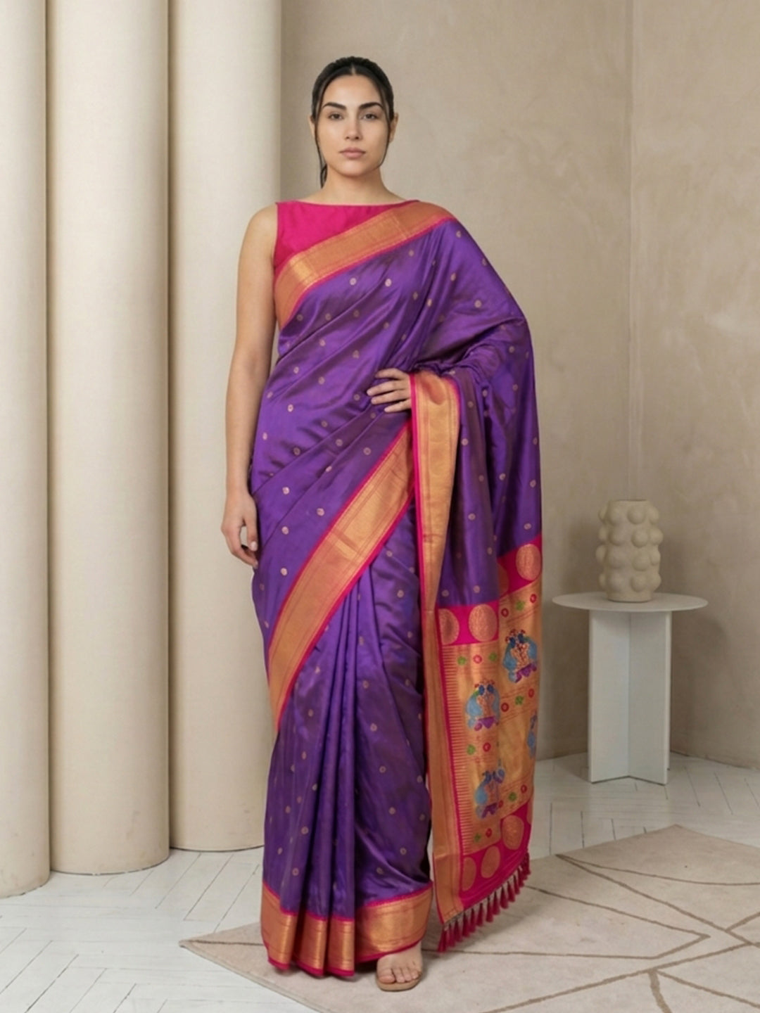 Woman wearing a purple saree with pink blouse in a neutral setting