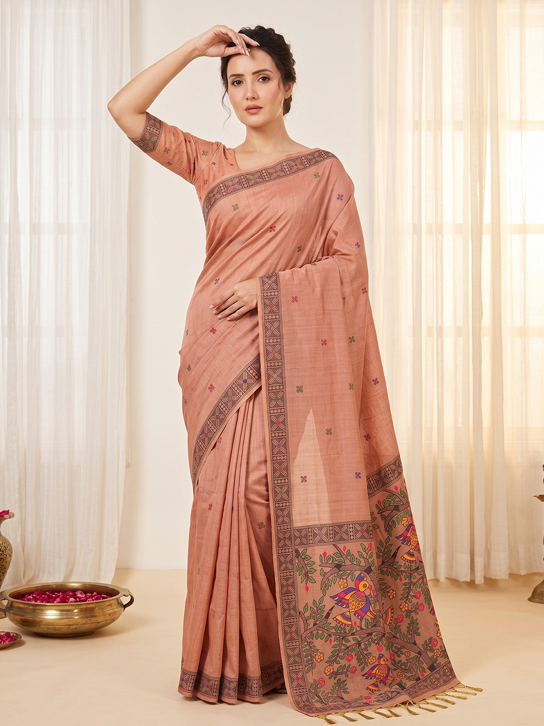 Woman wearing a traditional saree with intricate patterns in a well-lit room.