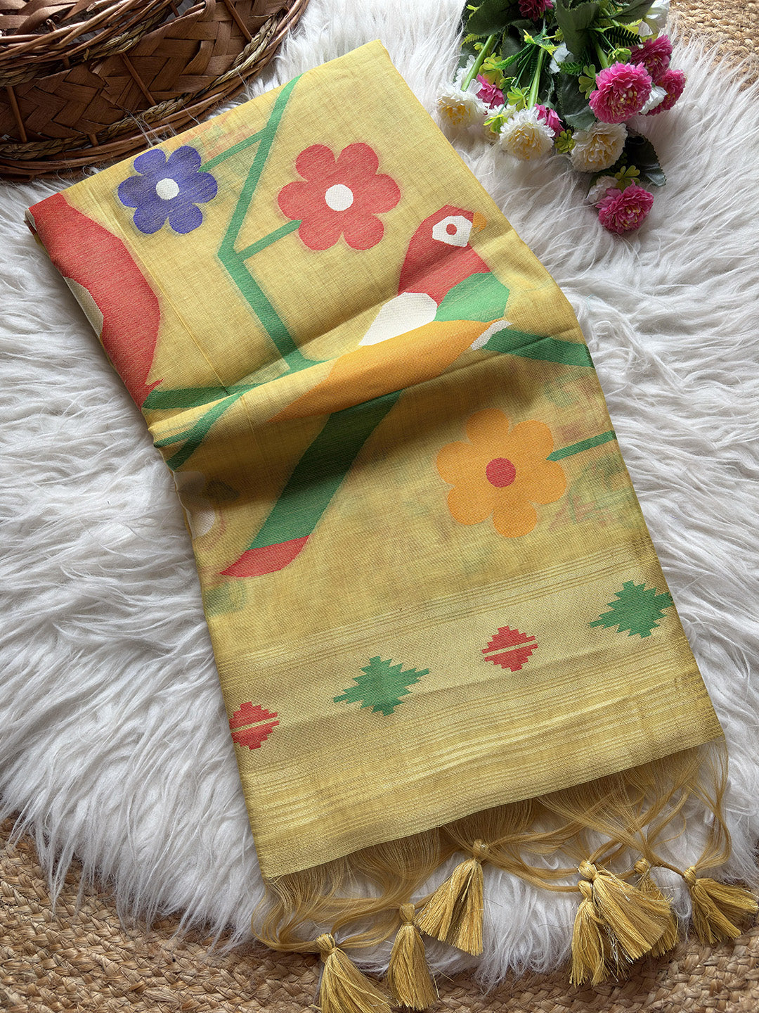 Yellow fabric with colorful floral and parrot designs on a textured surface.