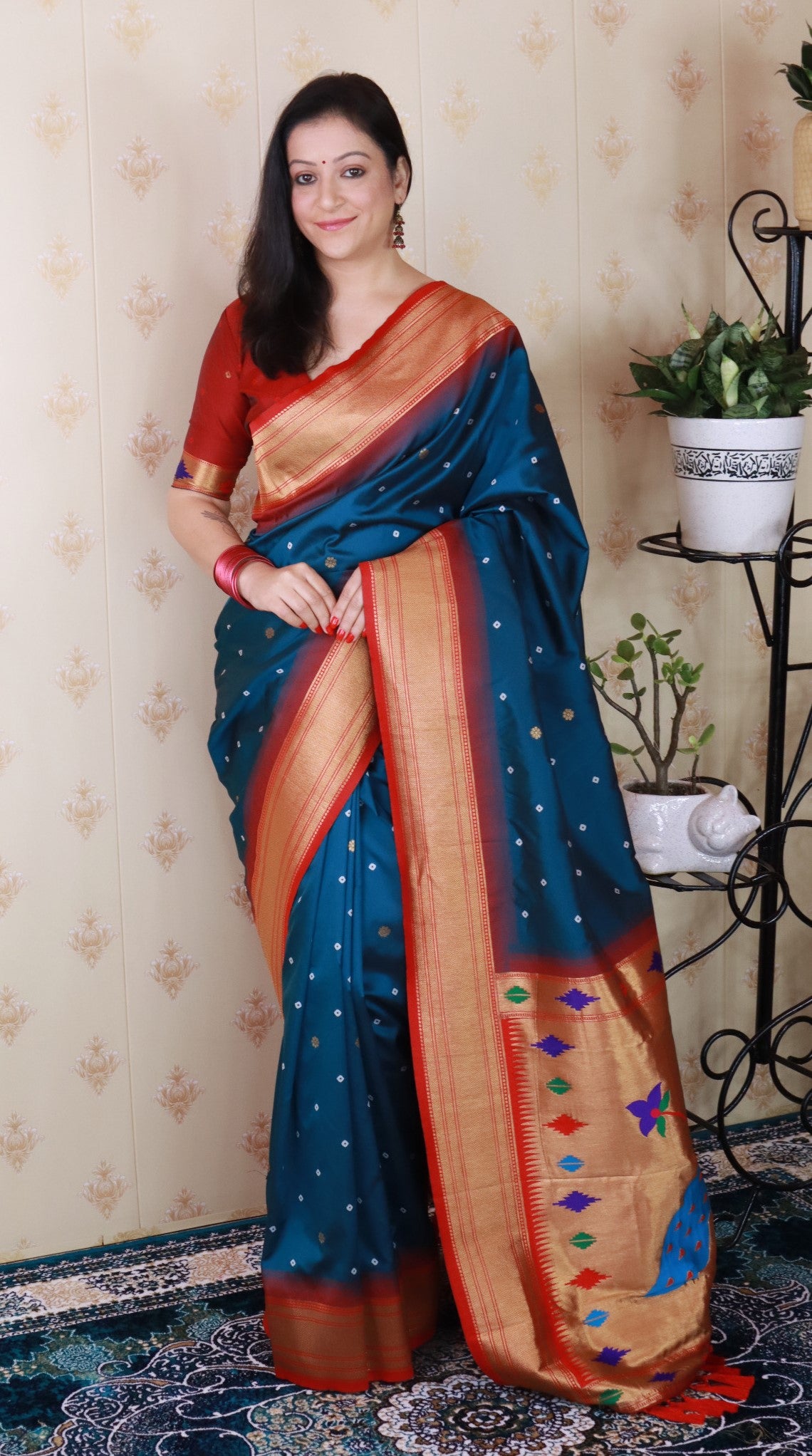 Woman wearing a blue saree with a pattern, standing indoors.