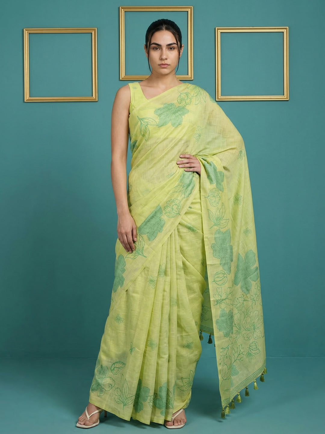 Woman wearing a light green saree with floral patterns against a teal background