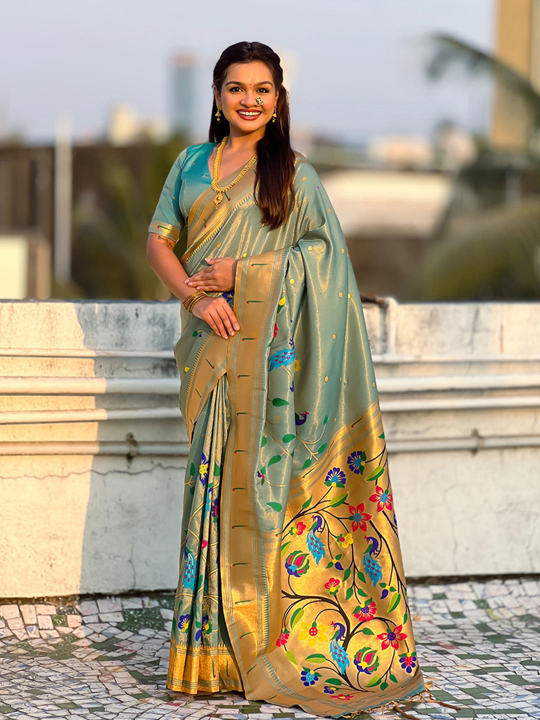 Woman wearing a traditional saree with floral patterns outdoors.