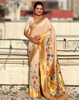 Woman in a beige saree with floral patterns standing on a rooftop.