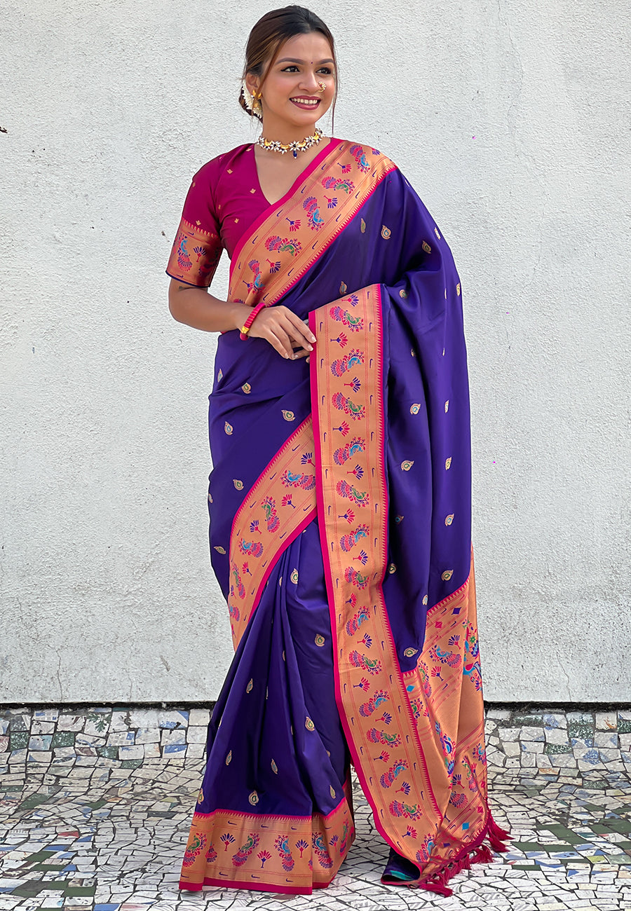 Woman wearing a purple and pink saree with a white wall background