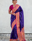Woman wearing a purple and pink saree with a white wall background