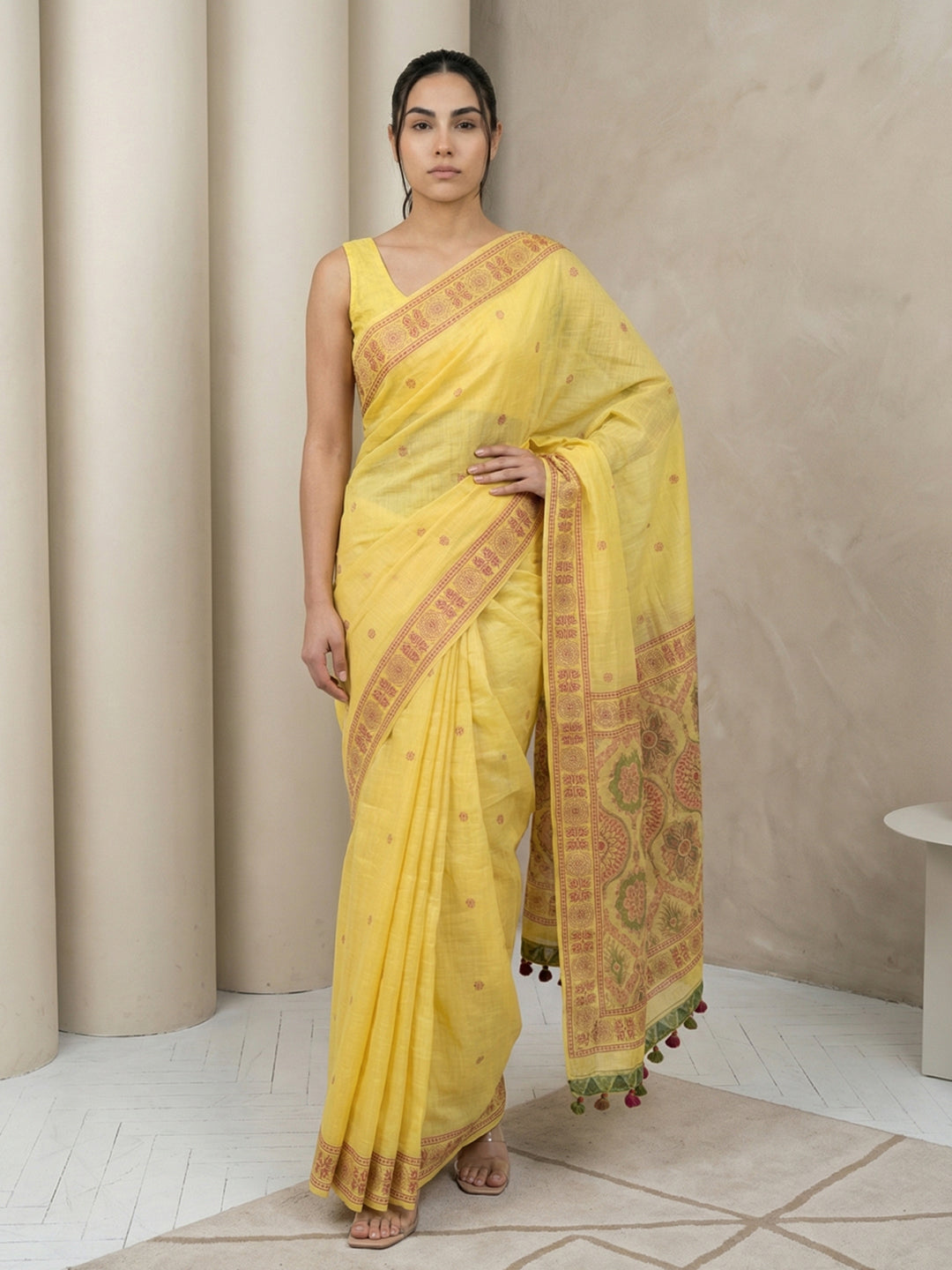 Woman wearing a yellow saree with a beige background