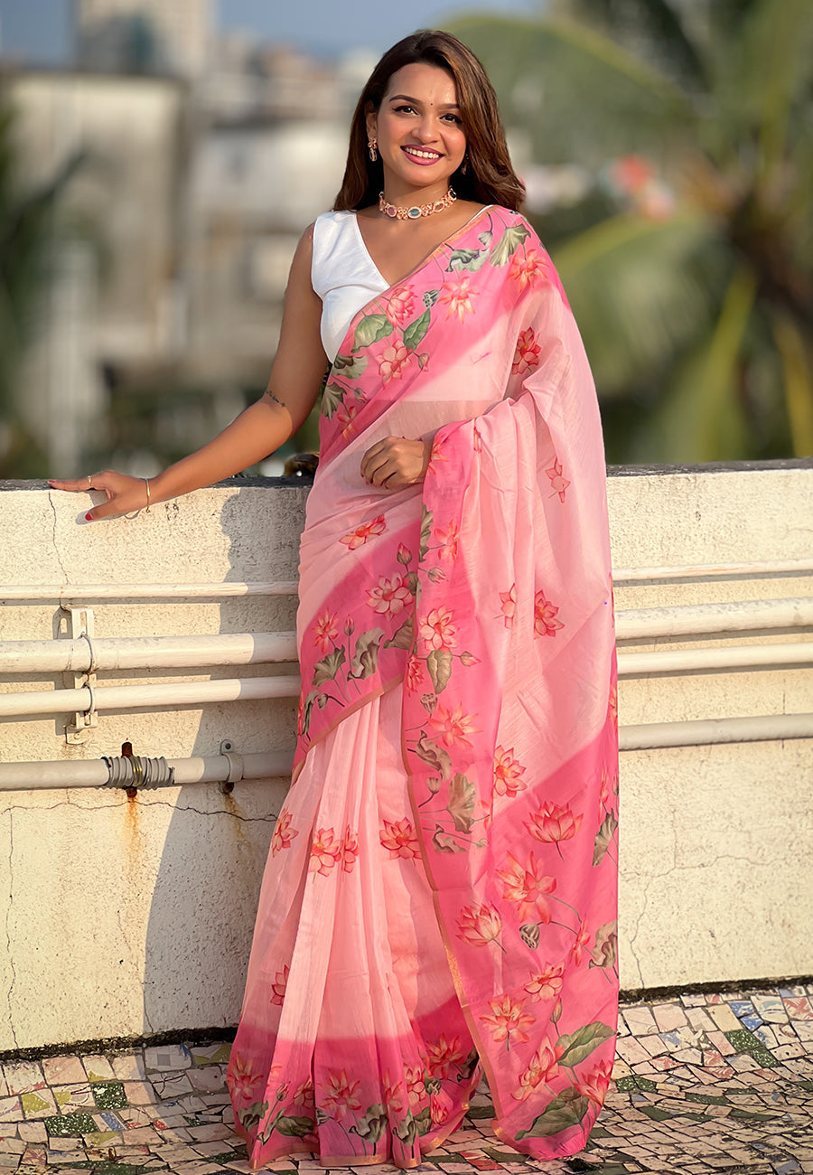 Woman wearing a pink saree with floral patterns outdoors.