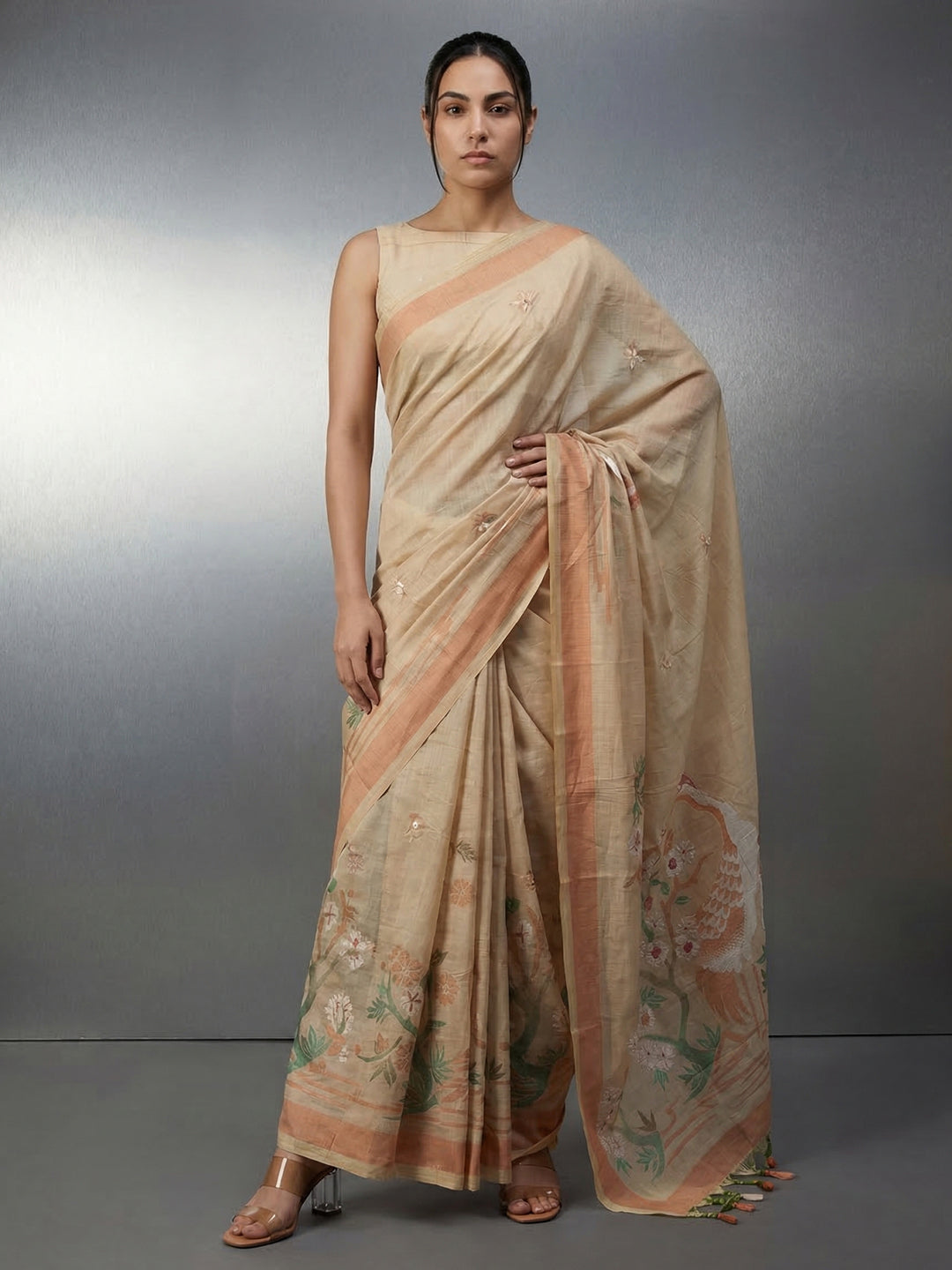 Woman wearing a beige saree with a subtle pattern on a gray background