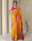 Woman wearing a yellow saree with pink border indoors
