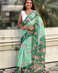 Woman wearing a green floral saree with a blurred background