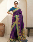 Woman wearing a purple saree with gold border in a room setting