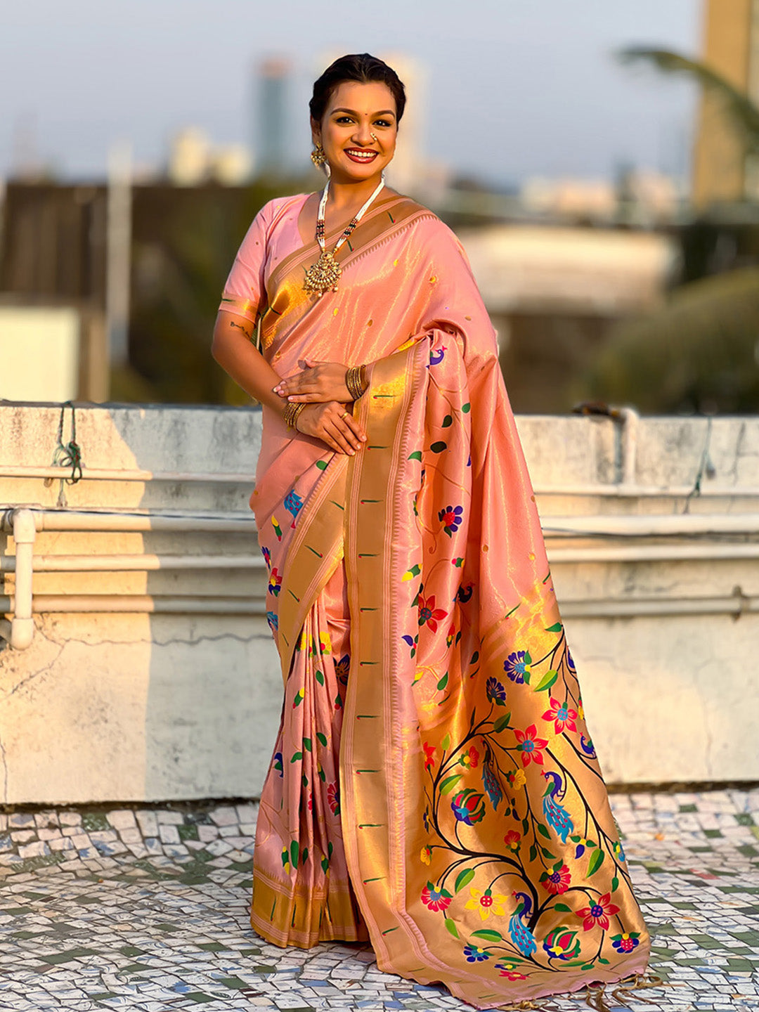 Woman wearing a traditional saree with a colorful design outdoors.